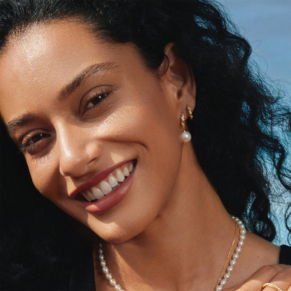 Niche Jewellery Ania Haie Shell Pearl Dangling Twisted Huggie Hoop Gold Earrings worn on model