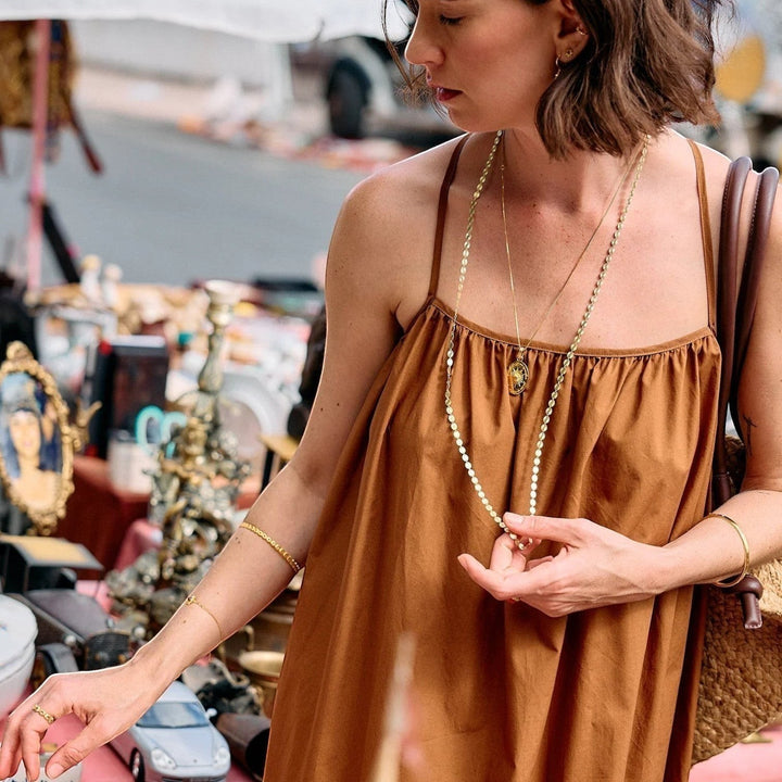 Woman wearing a long gold Rachel Jackson sunburst chain necklace with oval links, layered with a shorter chain.