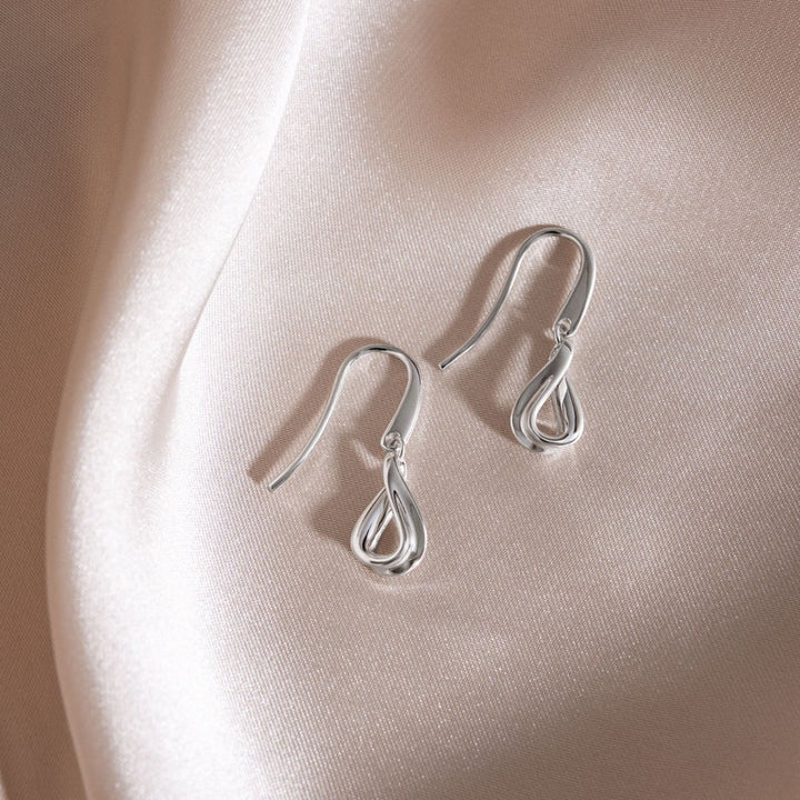 Kit Heath Serenity Loop Mini Drop Earrings in rhodium-plated sterling silver with fluid, twisted drop design.