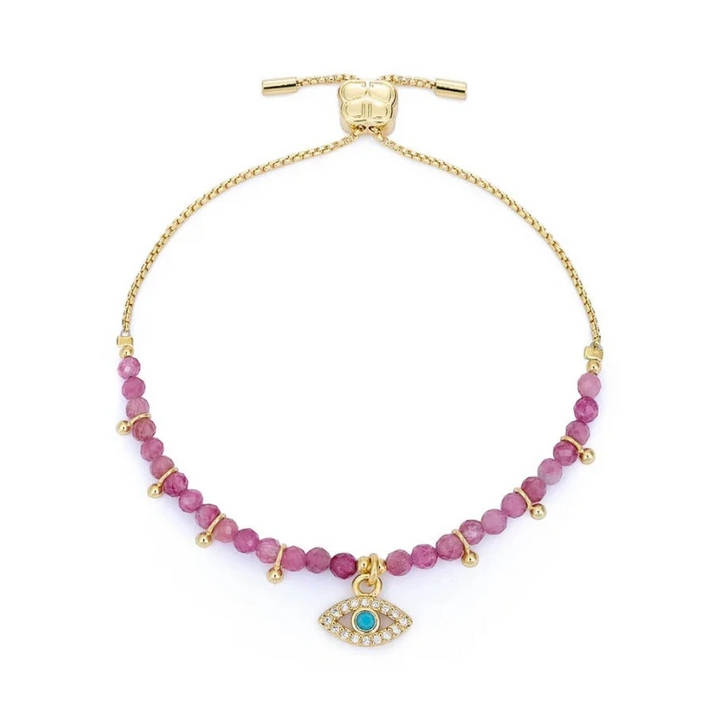 Gold bracelet with pink beads and a blue evil eye charm on a white background