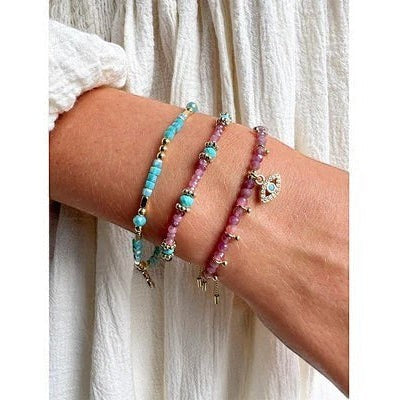 Close-up of a wrist wearing beaded Boho Betty bracelets with turquoise and pink beads.