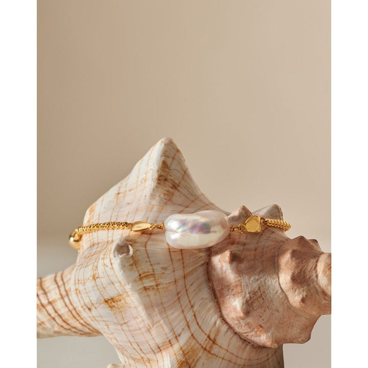 Niche Jewellery Sol Pearl bracelet with a large baroque pearl on a gold chain, set against a seashell.