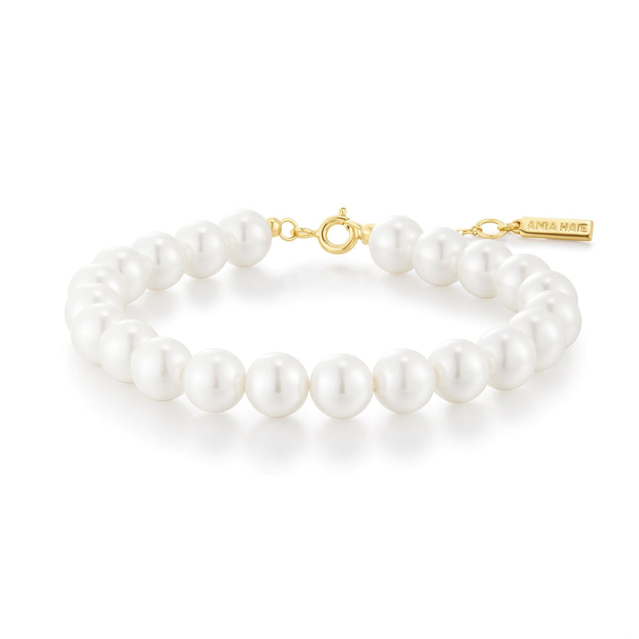Niche Jewellery Ania Haie shell pearl beaded bracelet with gold-toned clasp and branded charm on white background