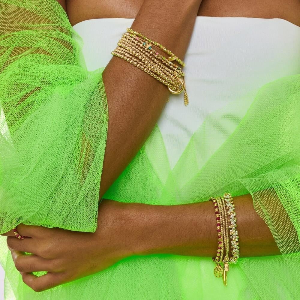 Niche Jewellery Annie Haak gold-plated silver bracelet stack with neon beads and a butterfly charm on a model's wrist.