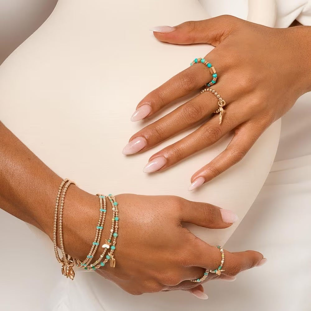 Niche Jewellery Annie Haak Papillon gold stretch bracelet with turquoise beads and a central butterfly charm on a model