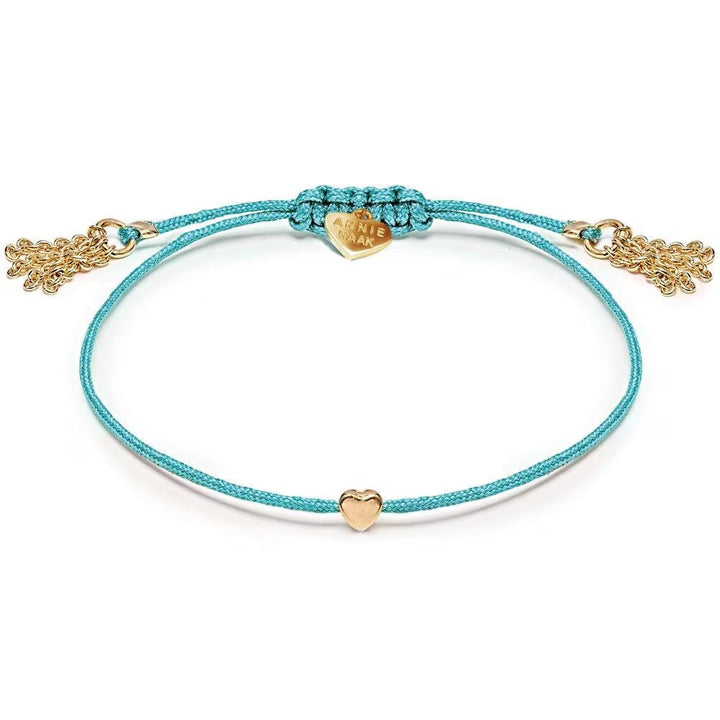 Niche Jewellery Annie Haak Harmony Heart bracelet in turquoise cord with a gold-plated heart charm and tassel ends.