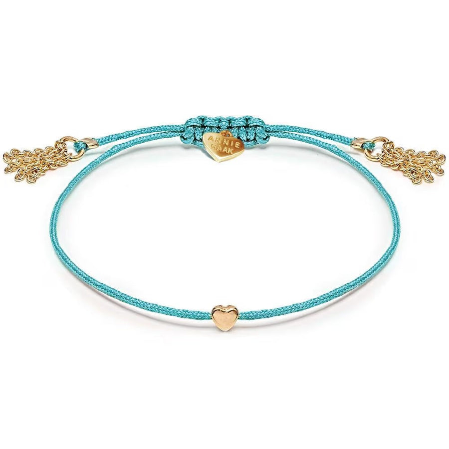 Niche Jewellery Annie Haak Harmony Heart bracelet in turquoise cord with a gold-plated heart charm and tassel ends.