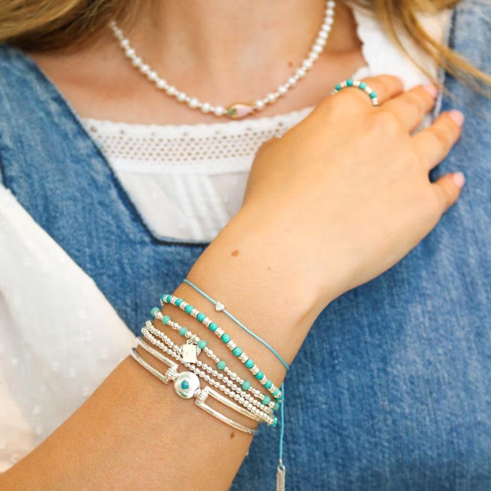 Niche Jewellery Annie Haak Harmony Heart gold-plated and turquoise bead stacking bracelet on a model's wrist.