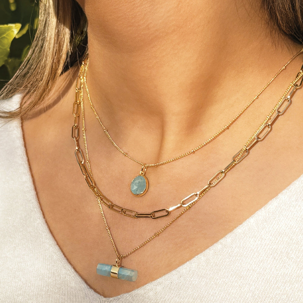 Niche Jewellery Sarah Alexander aquamarine gemstone pendant necklace layered on a gold bobble chain