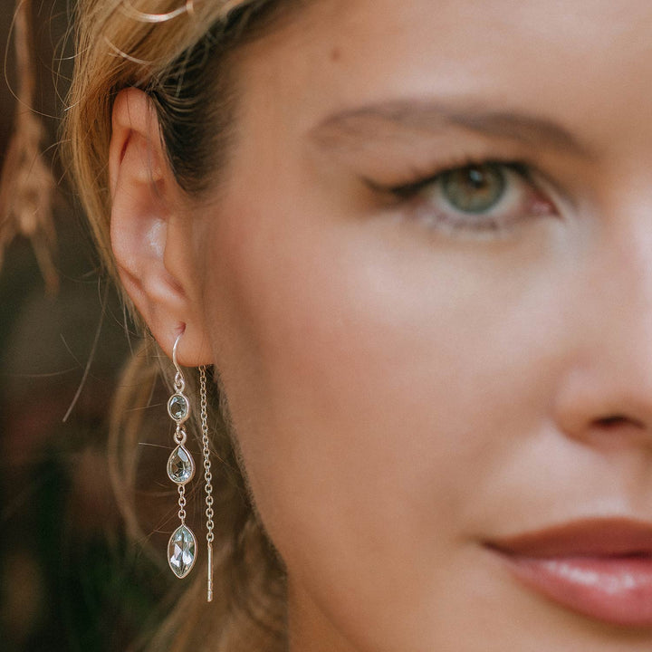 Niche Jewellery Charlotte's Web Azura sterling silver threader earrings with blue topaz stones worn by a woman