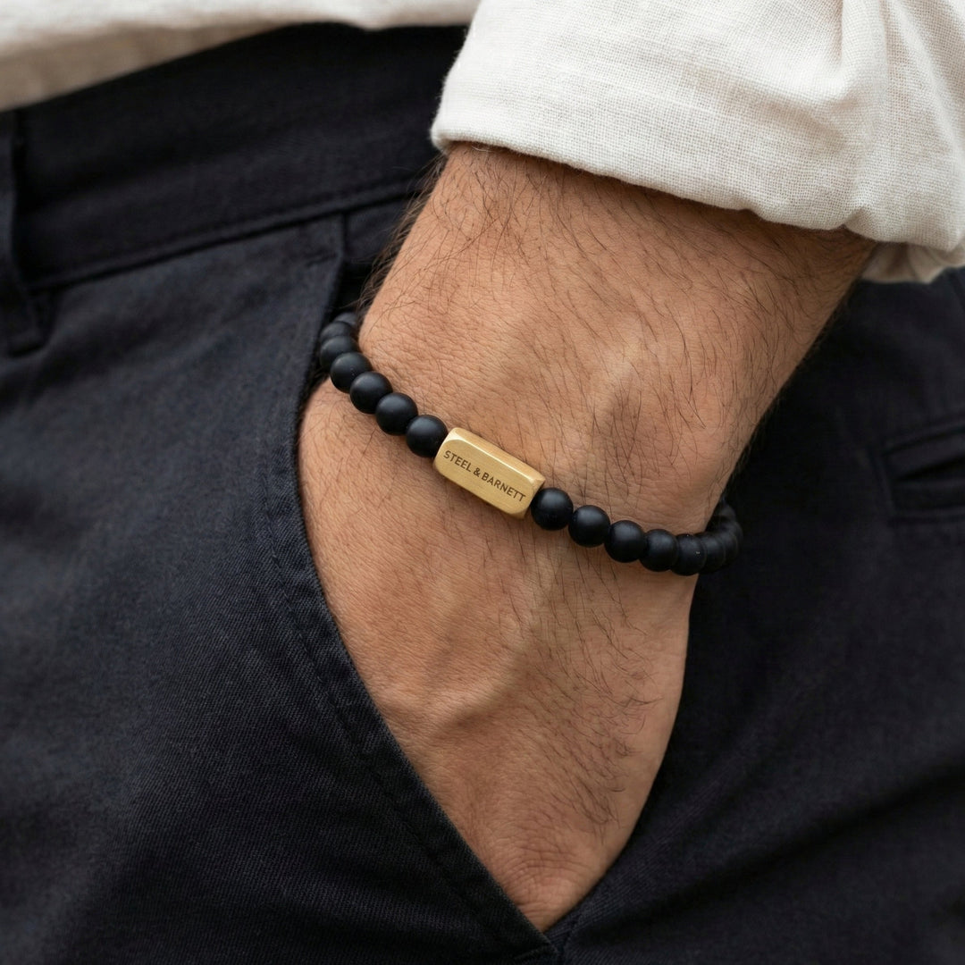 Niche Jewellery Steel & Barnett black onyx bead bracelet with a brushed 18K gold plated stainless steel logo bar.