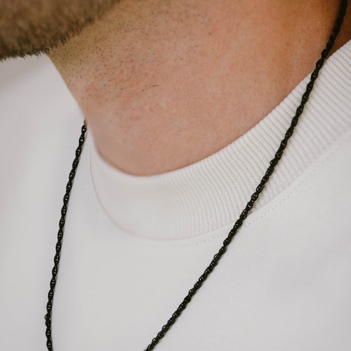 Niche Jewellery black stainless steel twisted rope chain necklace worn on a man in a white crew neck shirt