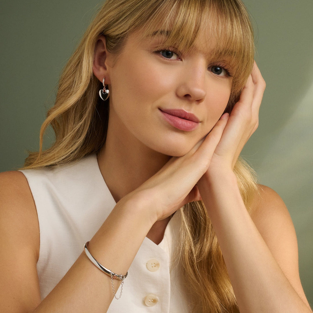 Niche Jewellery Clogau Cariad sterling silver bangle with rose gold heart detail worn by a blonde woman