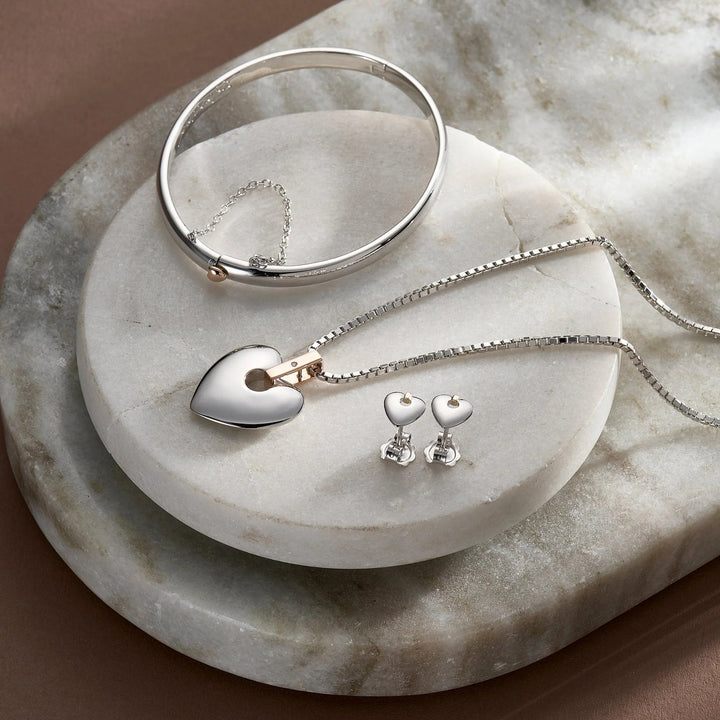 Niche Jewellery Clogau Cariad sterling silver bangle, heart pendant necklace, and stud earrings with rose gold detail.