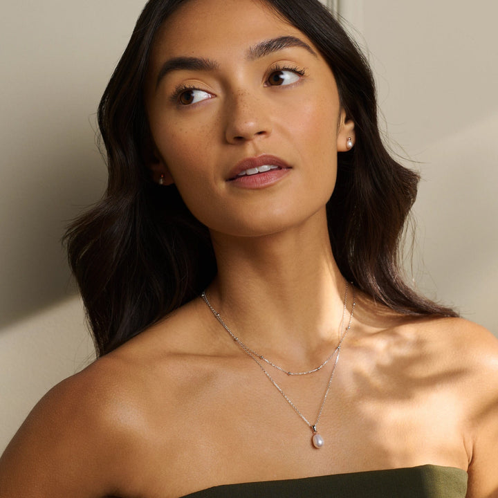Niche Jewellery Clogau sterling silver and freshwater pearl stud earrings worn by a woman with a matching necklace