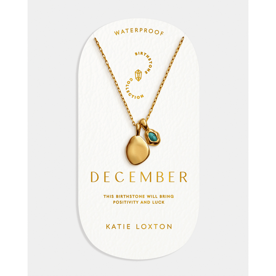 Niche Jewellery Katie Loxton December birthstone necklace with a gold-tone chain and blue stone on display card.