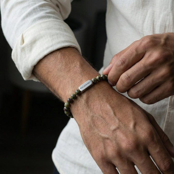Niche Jewellery Steel & Barnett 6mm dragon's blood jasper bead bracelet with stainless steel accent on a man's wrist.