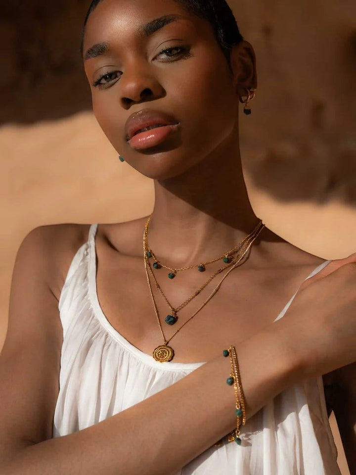 Niche Jewellery Formation Co Mohica emerald charm bracelet in 18k gold plated silver worn by a model in sunlight