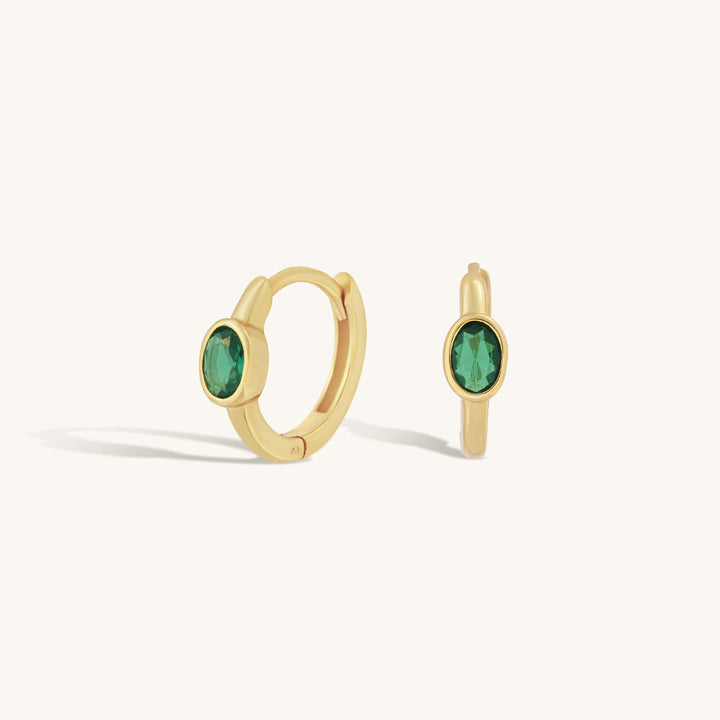 Niche Jewellery Boheme emerald huggie earrings in 18k gold plated sterling silver with oval green stones.