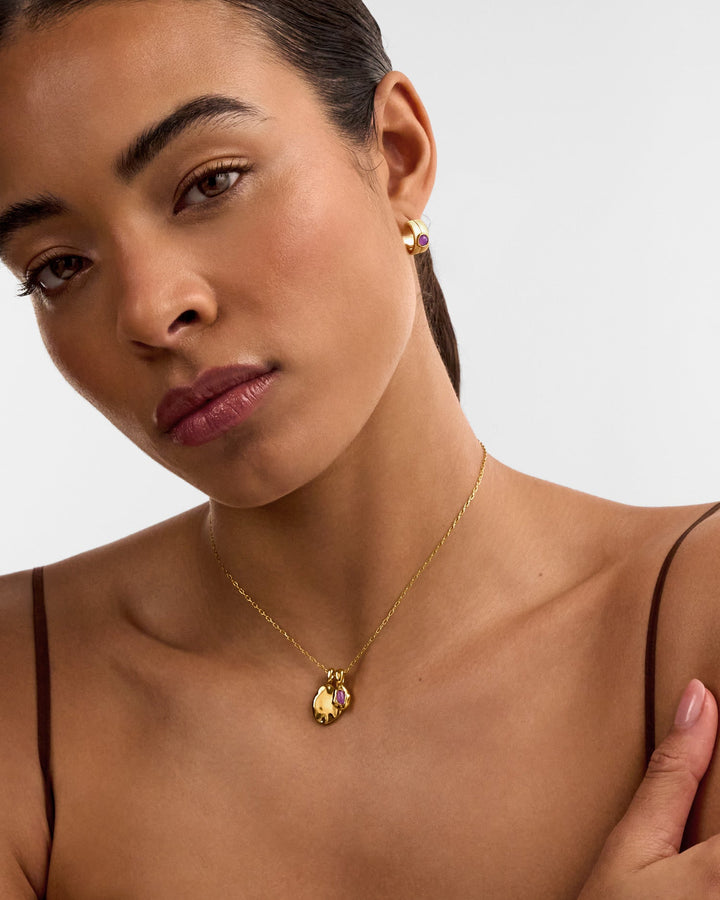 Niche Jewellery Katie Loxton February birthstone necklace with a purple stone on a gold chain worn by a model