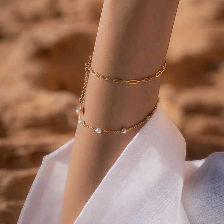 Niche Jewellery Formation Co Gaia pearl bracelet with freshwater pearls on an 18k gold plated chain worn on a wrist at the beach.
