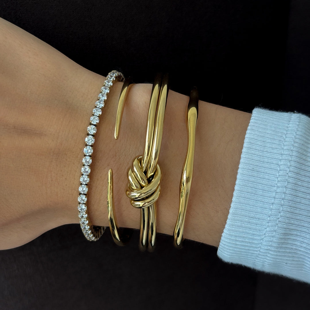 Niche Jewellery gold bamboo knot bangle stacked with a diamond tennis bracelet and a plain gold cuff.