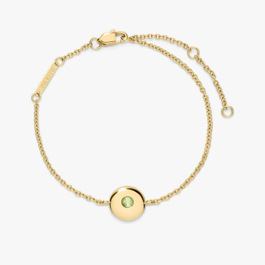 Niche Jewellery gold chain bracelet with a round charm featuring a green peridot birthstone. Adjustable clasp closure.