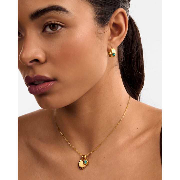 Niche Jewellery Katie Loxton December birthstone necklace in gold with a blue stone worn by a woman