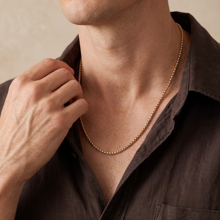 Niche Jewellery Steel & Barnett thin gold box chain necklace worn by a man in a dark brown linen shirt