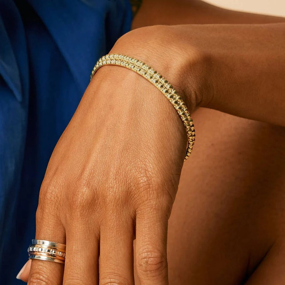 Niche Jewellery Charlotte's Web gold vermeil Maharani stacking bangle with delicate bubble texture worn on a woman's wrist.