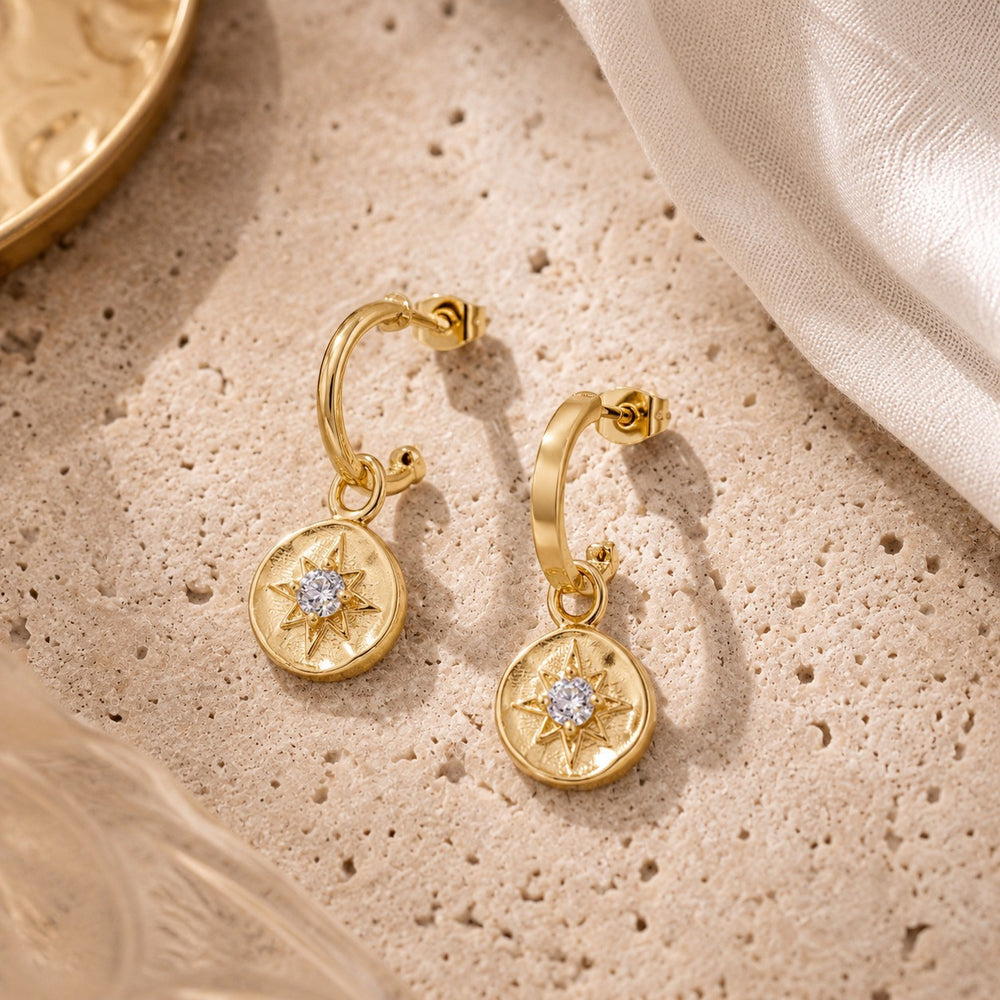 Niche Jewellery Formation Co gold plated sterling silver huggie earrings featuring celestial star charms with diamante accents.