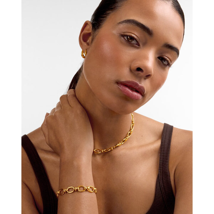 Niche Jewellery Katie Loxton Empire gold chain bracelet and matching necklace worn by a woman in a brown tank top.