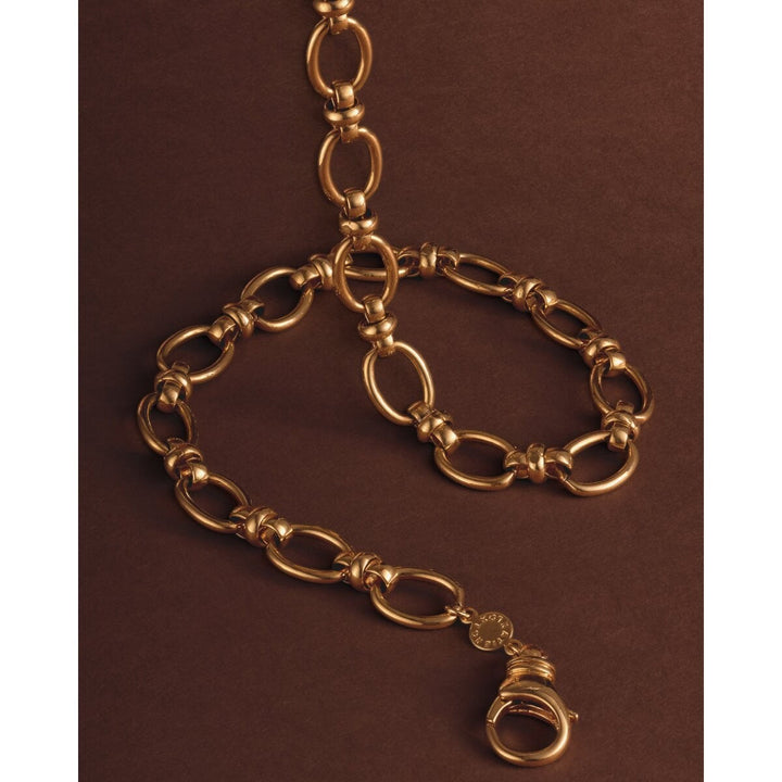 Niche Jewellery Katie Loxton Empire waterproof gold-tone chain necklace with heavy oval links on a brown background.