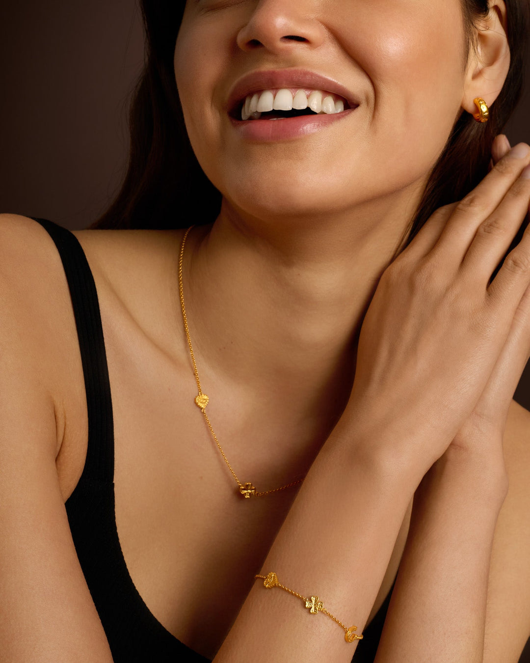 Niche Jewellery Katie Loxton gold-tone waterproof charm bracelet worn on a model's wrist with matching necklace
