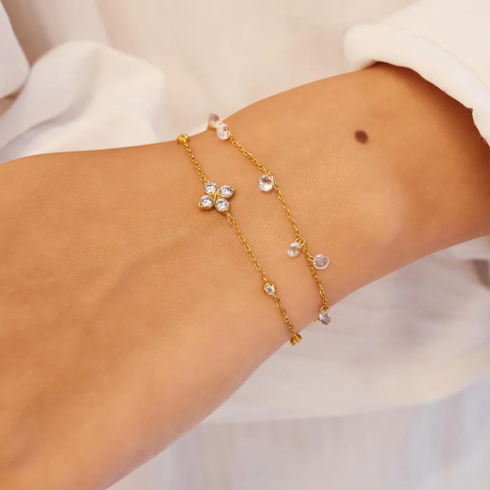 Niche Jewellery Ania Haie gold chain bracelet featuring a sparkling four-leaf clover charm with clear crystal stones.