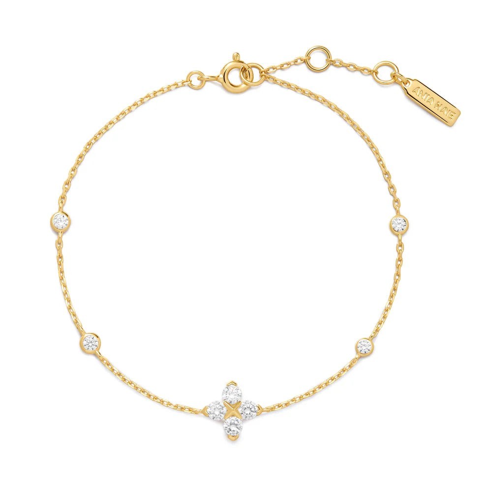 Niche Jewellery Ania Haie gold chain bracelet featuring a sparkling four-leaf clover charm and bezel-set crystals.