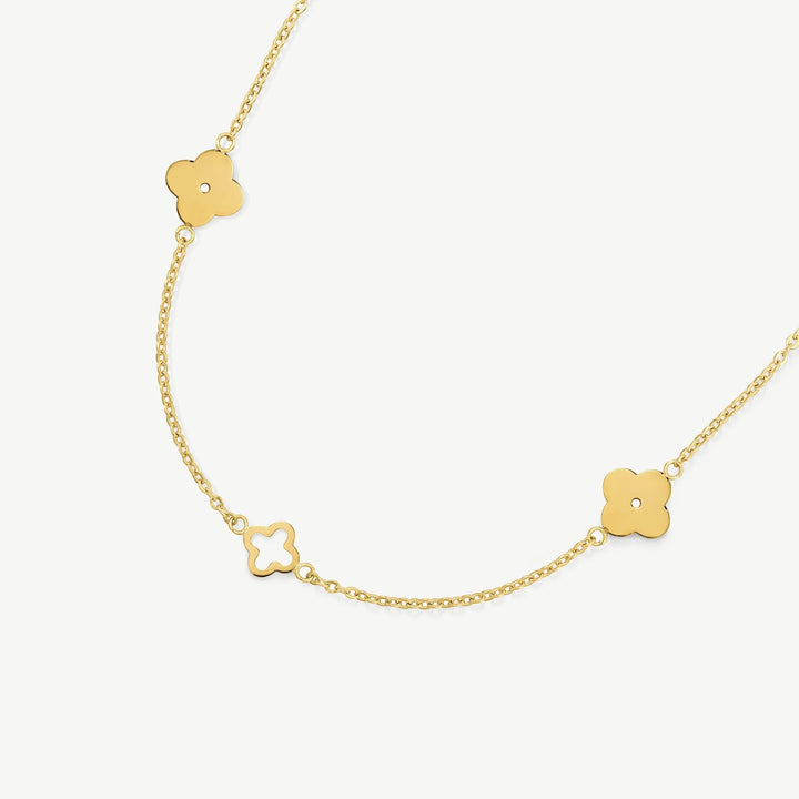 Niche Jewellery gold clover necklace featuring solid and cut-out clover charms on a delicate stainless steel chain.