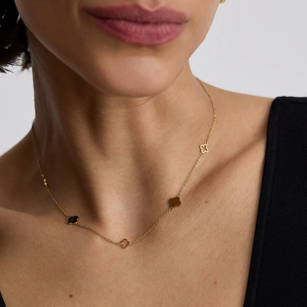 Niche Jewellery D.Louise gold clover necklace with delicate cut-out and solid charms worn on a model's neck.