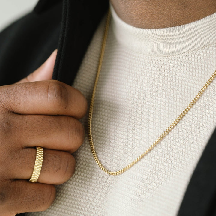 Niche Jewellery thin 18K gold plated stainless steel curb chain necklace worn by a man with a matching gold ring.