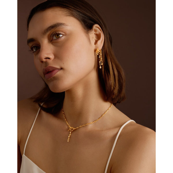 Niche Jewellery Katie Loxton gold drop earrings with sparkling accents worn by a model in a studio setting
