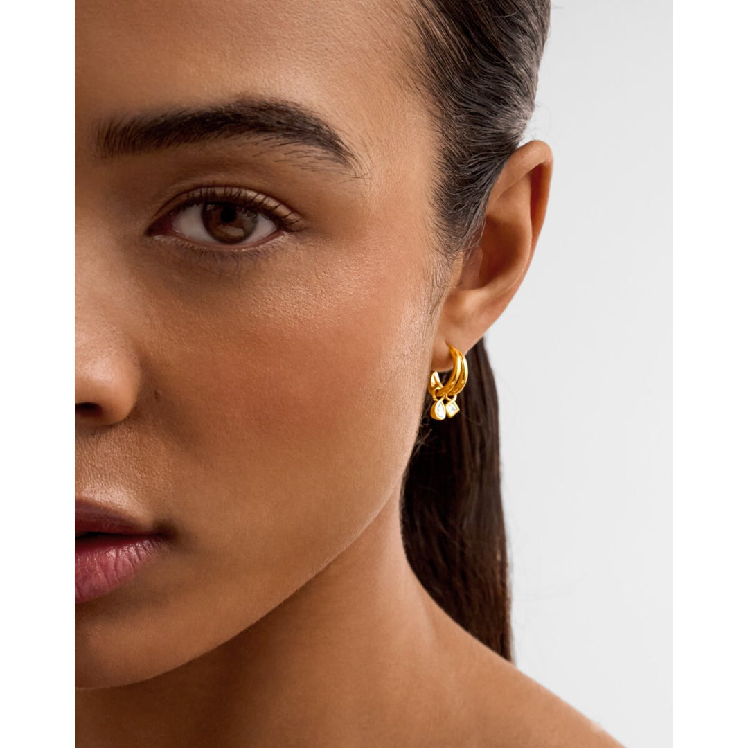 Niche Jewellery Katie Loxton gold waterproof drop earrings worn on a model, featuring double hoops and small charms.