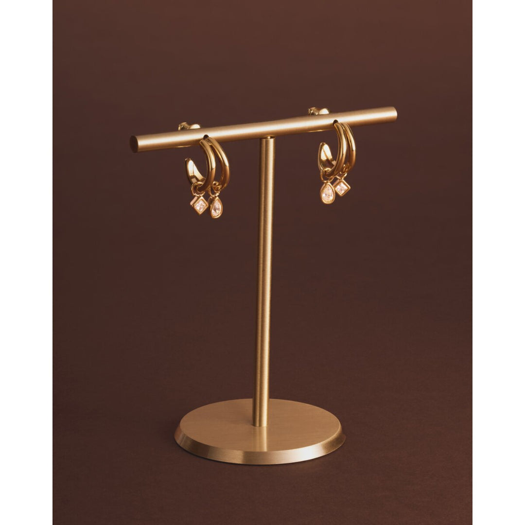Niche Jewellery Katie Loxton gold-tone waterproof drop earrings with sparkling charms on a display stand.