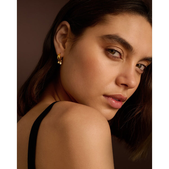 Niche Jewellery Katie Loxton gold waterproof double hoop drop earrings worn by a woman looking over her shoulder