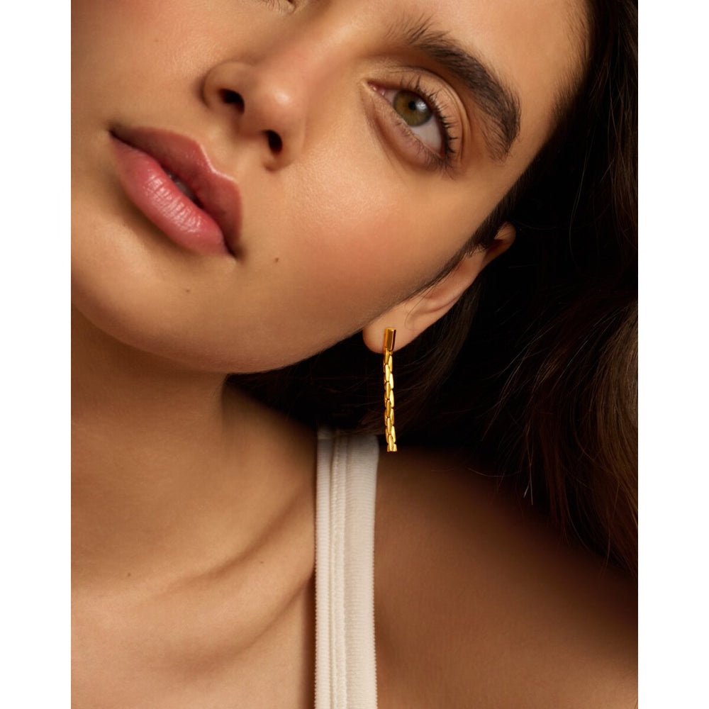 Niche Jewellery Katie Loxton gold drop stud earrings with diamond-check pattern worn by a model