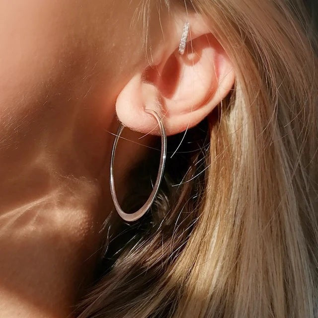 Niche Jewellery Scream Pretty gold-plated flat hoop earrings worn on a model with a small crystal ear cuff