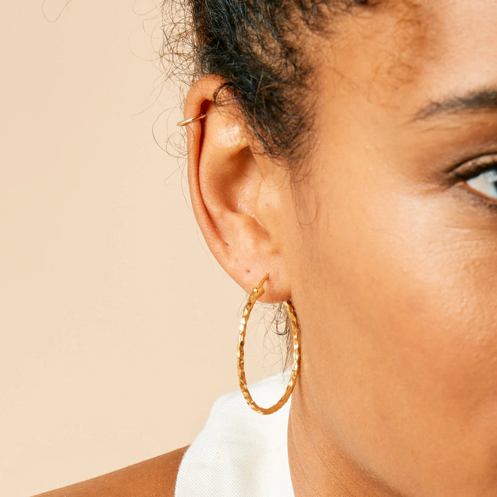 Niche Jewellery Charlotte's Web gold hammered hoop earrings worn on a model's ear