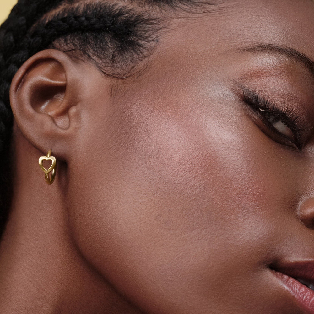 Niche Jewellery Olivia Burton Kindred gold-plated hoop earrings featuring an interlinking heart design on a model.