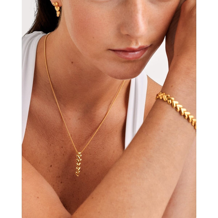 Niche Jewellery Katie Loxton gold necklace with a vertical row of five heart-shaped links on a delicate chain. Waterproof and sweat-proof.
