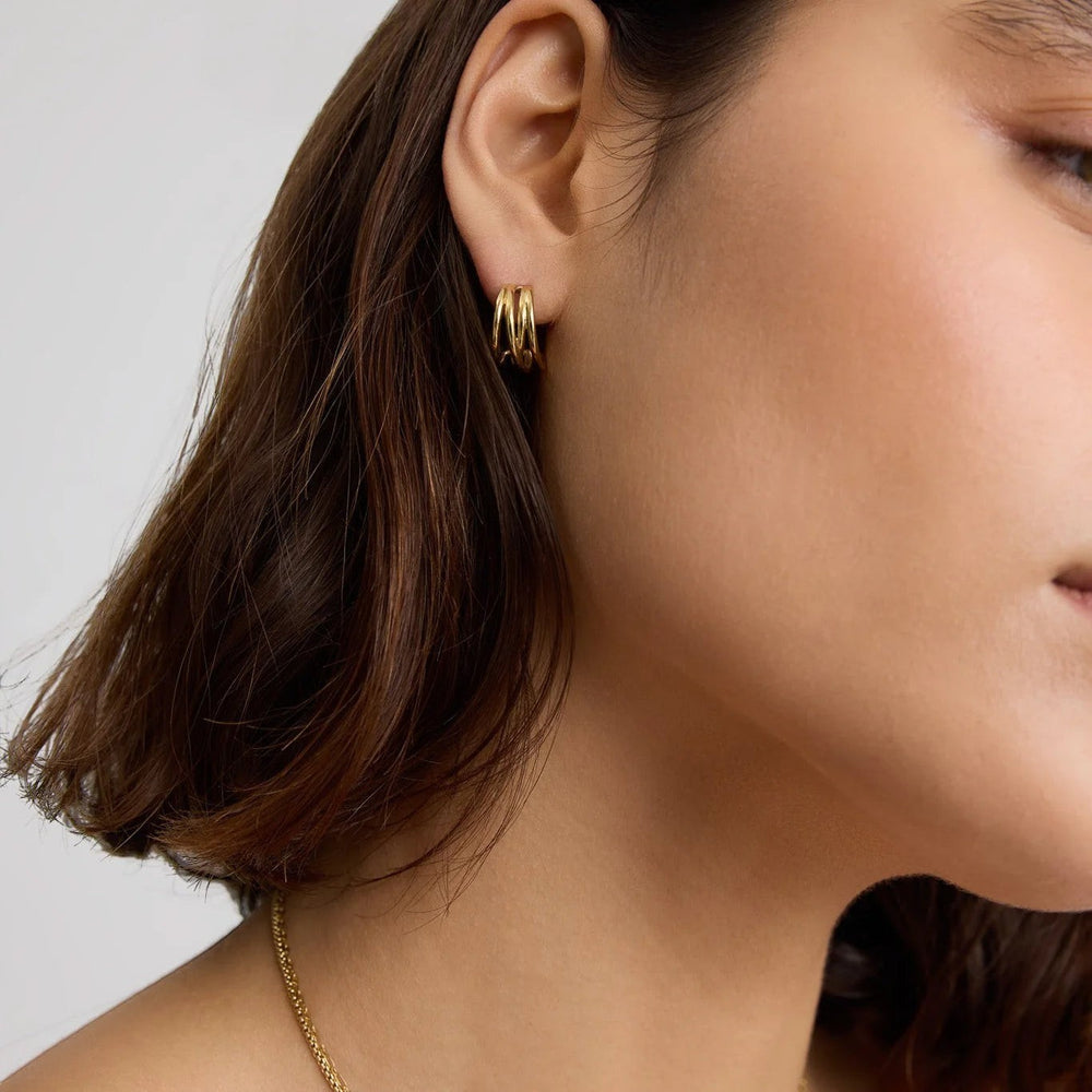 Niche Jewellery D.Louise gold intertwined mini hoop earrings worn on a model, featuring a polished twisted design.