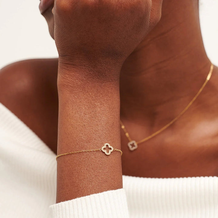 Niche Jewellery D.Louise gold pavé clover bracelet on a model's wrist, featuring a delicate chain and sparkling charm.